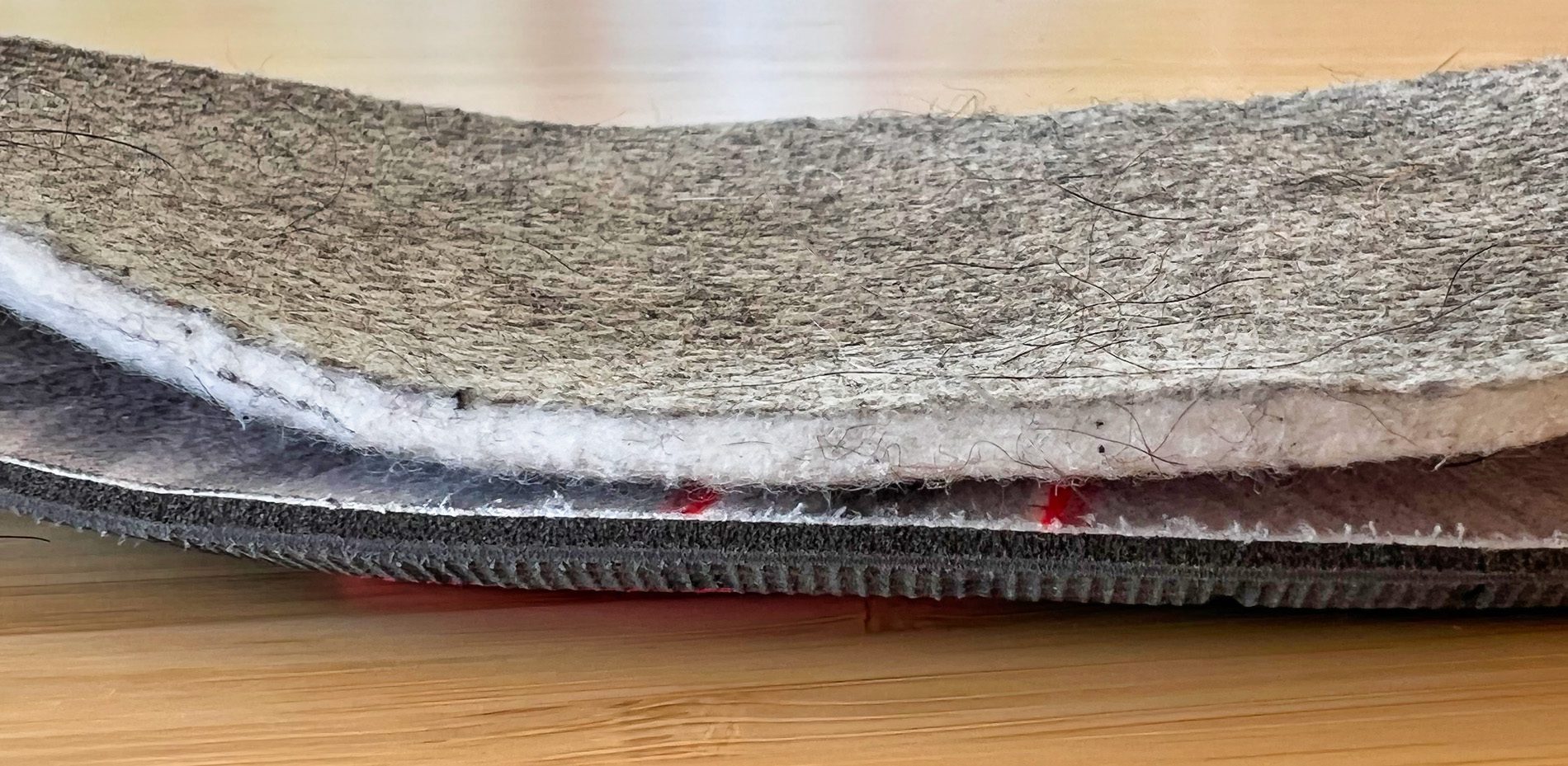 Im Foto sieht man unten die Orthomove EInlagen und oben die Einlagen, die vom Hersteller in die Schuhe gepackt wurden. Man sieht deutlich, dass die oberen Einlegesohlen komplett aus einem weichen, wollartigem Gewebe bestehen, das keinerlei Stabilität gewährleisten kann.