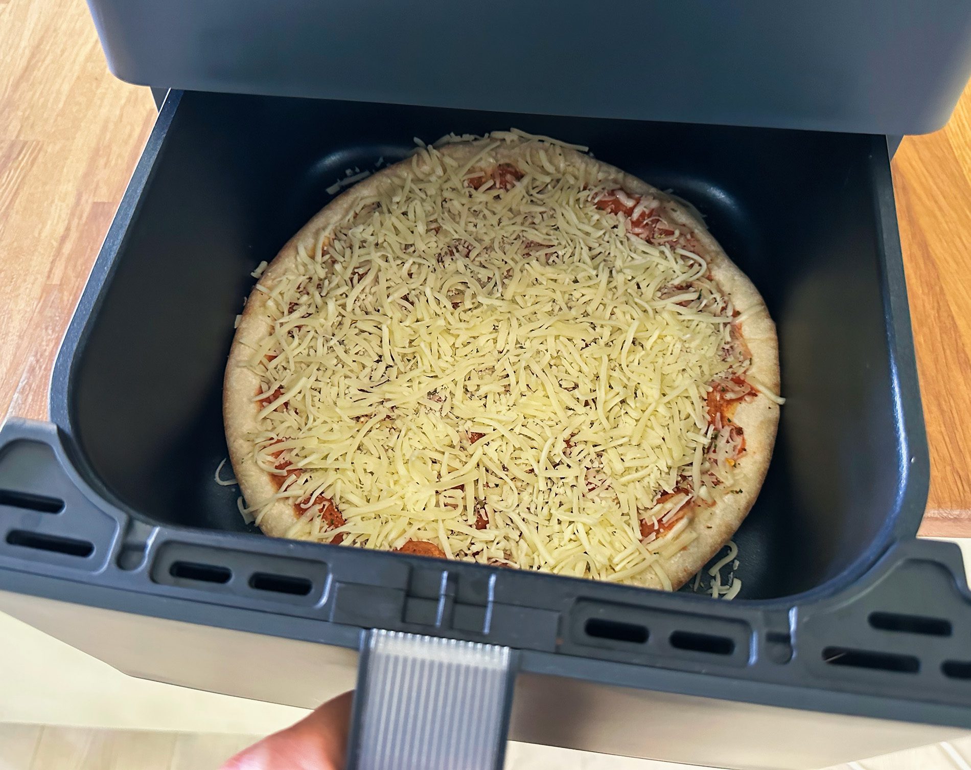 Hier die Fertigpizza, die ich noch etwas mit Käse gepimpt habe – vor dem Backen.