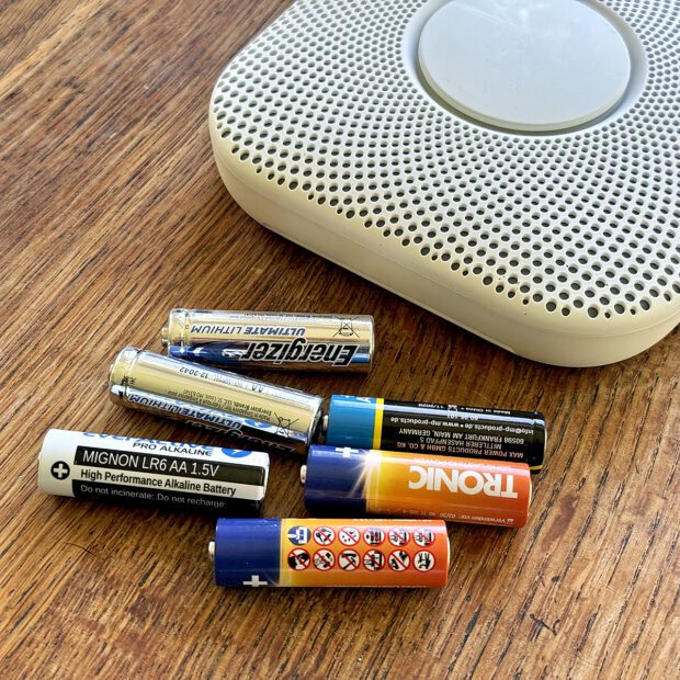 Batterien auf einem Tisch neben dem Nest Protect Rauchmelder von Google
